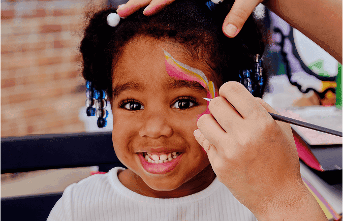 Young girl smiling while having her face painted