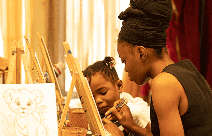 Mother helping her child paint at an easel