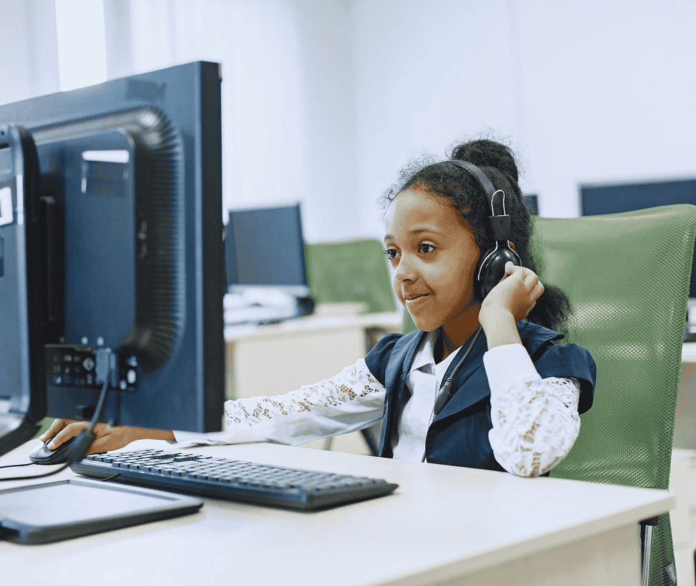 Young girl wearing headphones learning on a computer in a classroom